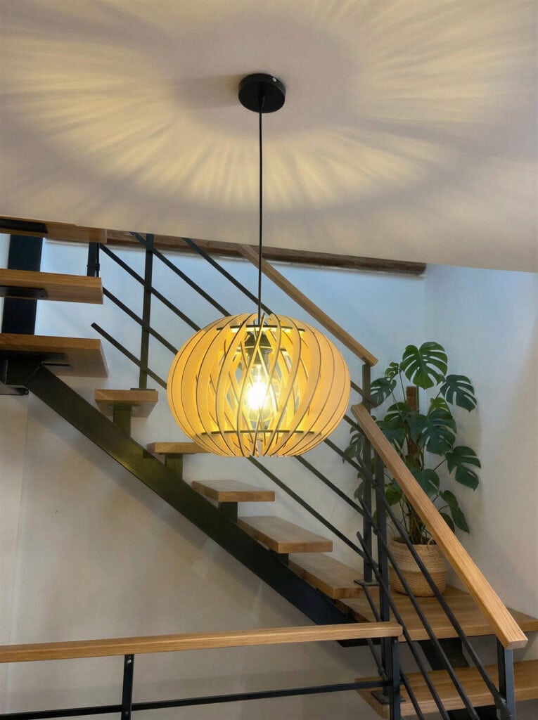 Suspension bois Alban éclairant une cage d'escalier avec marches bois et rampe métallique