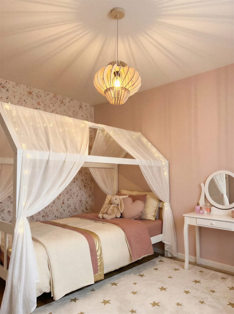 Suspension bois Odette en forme de planète dans une chambre d'enfant aux murs roses avec lit à baldaquin
