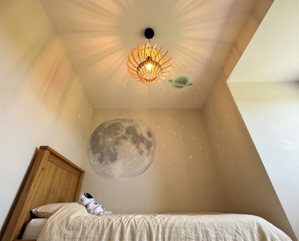 Suspension bois Odette en forme de planète éclairant une chambre d'enfant sous combles à la déco espace