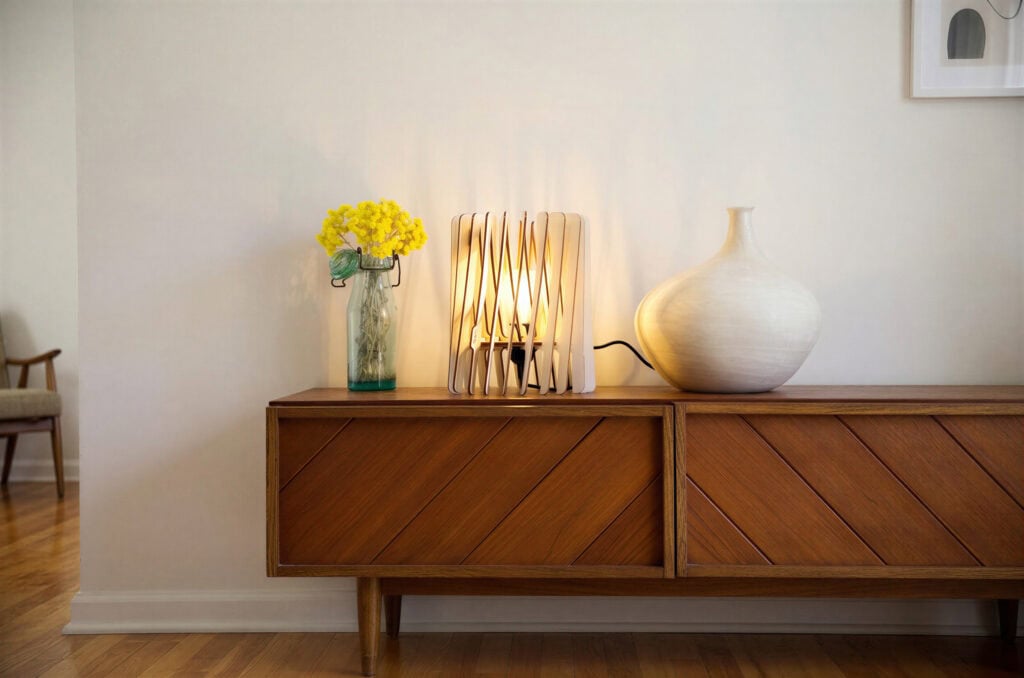 Luminaire déco design posé et allumé sur un buffet bas dans un salon minimaliste et moderne