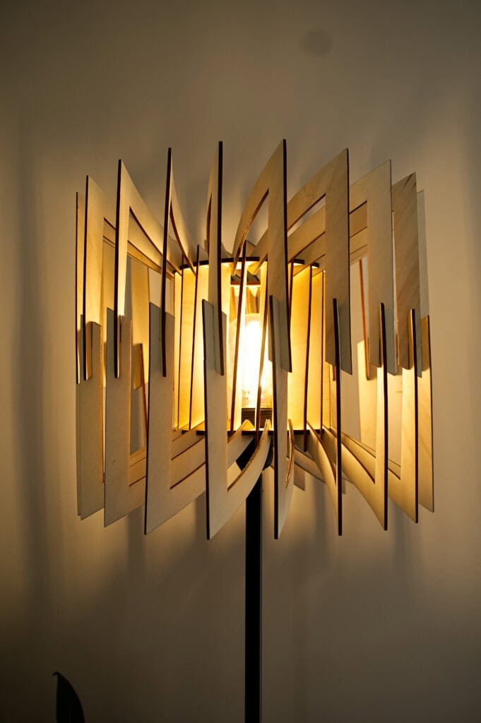 Lampadaire en bois Léon allumé, vu de face, montrant sa structure géométrique à facettes.