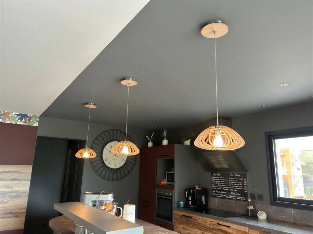 Suspensions bois en trio dans une cuisine ouverte avec plafond anthracite et sol bois